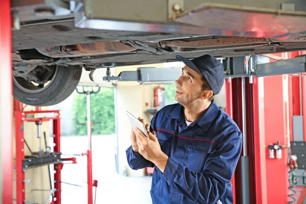 Male mechanic with tablet computer in car service center — Stock Photo, Image