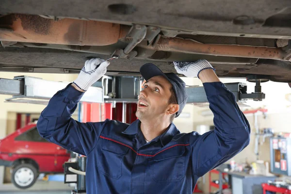 Male mechanic repairing car in service center — ストック写真