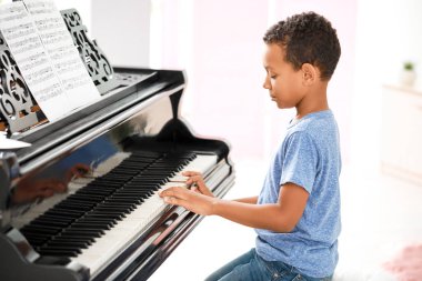 Küçük Afro-Amerikalı çocuk evde piyano çalıyor.