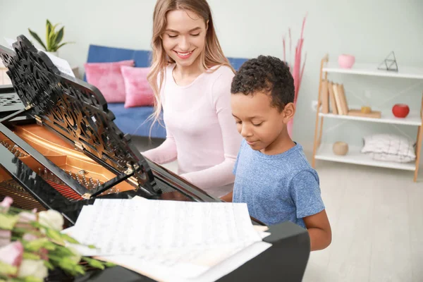 Kvinna undervisning Little Afro-American boy att spela piano hemma — Stockfoto