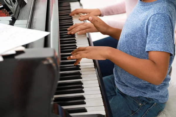 Donna che insegna al piccolo ragazzo afro-americano a suonare il pianoforte a casa — Foto Stock