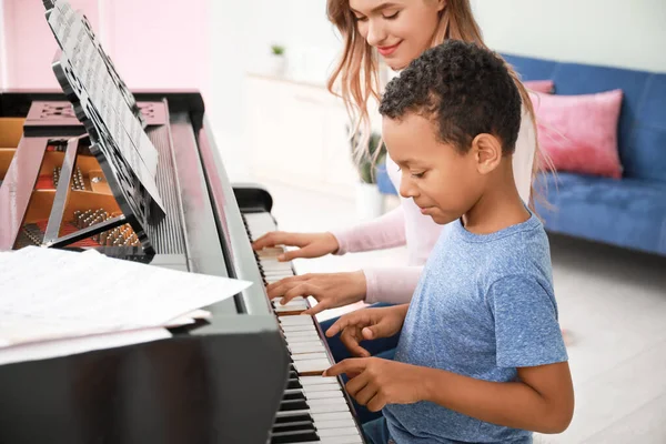 Kvinna undervisning Little Afro-American boy att spela piano hemma — Stockfoto