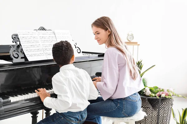 Woman teaching little African-American boy to play piano at home — Stock Photo, Image