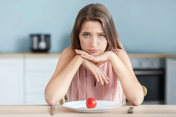 Traurige Frau mit frischen Tomaten auf dem Teller in der Küche. Ernährungskonzept — Stockfoto