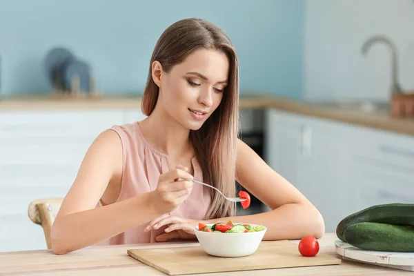 Genç bir kadın mutfakta sağlıklı sebze salatası yiyor. Diyet kavramı — Stok fotoğraf