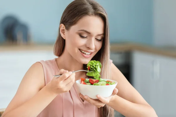 年轻女人在厨房吃健康的蔬菜沙拉. 饮食概念 — 图库照片