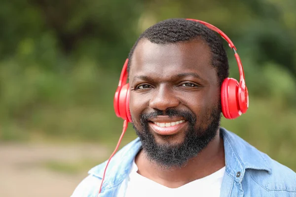 Handsome African-American man listening to music outdoors — Stock Photo, Image