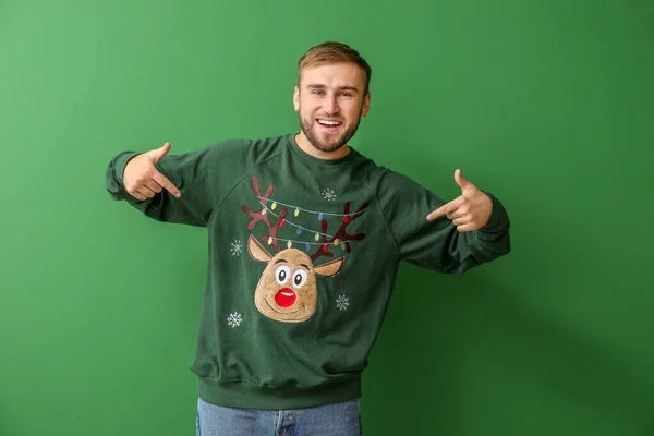 Young man in Christmas sweater on color background — Stock Photo, Image