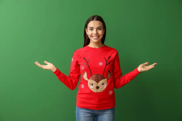 Mladá žena v vánoční svetr na barevném pozadí — Stock fotografie