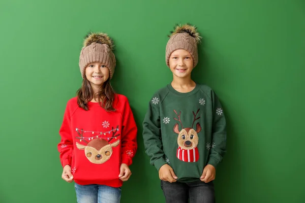 Små barn i jultröjor och stickade hattar på färg bakgrund — Stockfoto