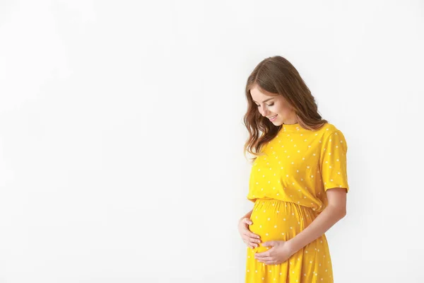 Schöne schwangere Frau auf hellem Hintergrund — Stockfoto