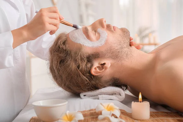 Cosmetoloog aanbrengen van masker op het gezicht van de mens in spa salon — Stockfoto