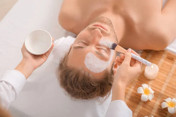 Cosmetologist applying mask onto man's face in spa salon — Stock Photo, Image