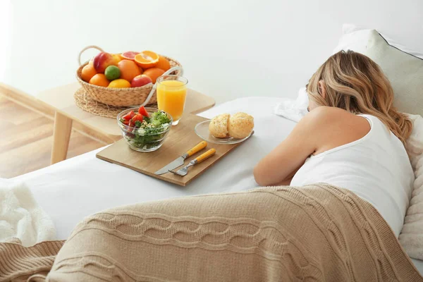 Plateau avec petit déjeuner savoureux sur le lit de la femme endormie — Photo