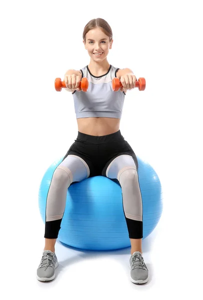 Sporty young woman training with dumbbells and fitball against white background — ストック写真