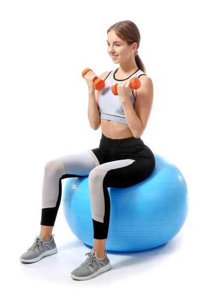 Sporty young woman training with dumbbells and fitball against white background — ストック写真