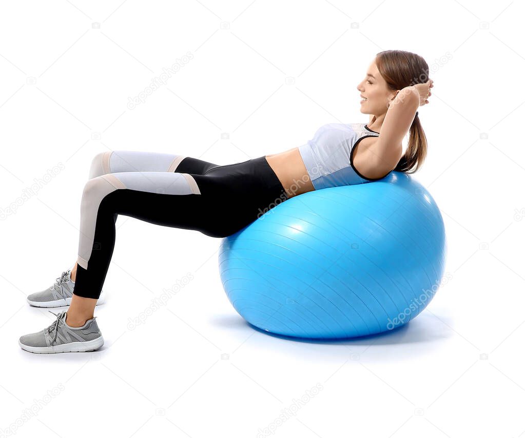 Sporty young woman training with fitball against white background