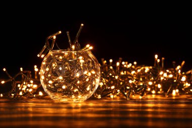 Masada parlayan Noel ışıkları olan vazo.