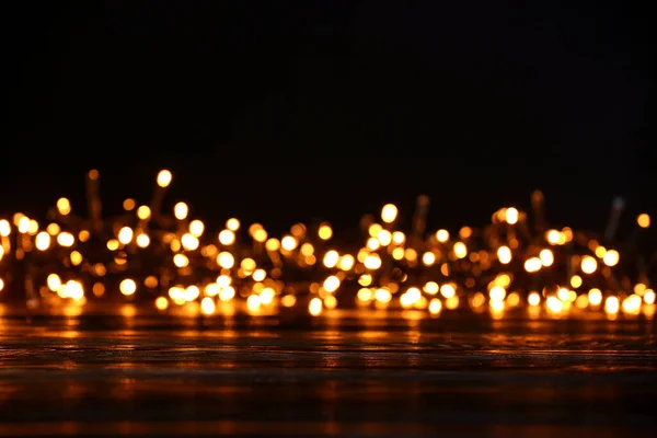 Mesa de madeira e luzes de Natal borradas, close-up — Fotografia de Stock