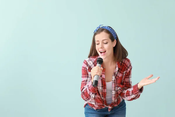 Linda jovem cantora com microfone no fundo de cor — Fotografia de Stock