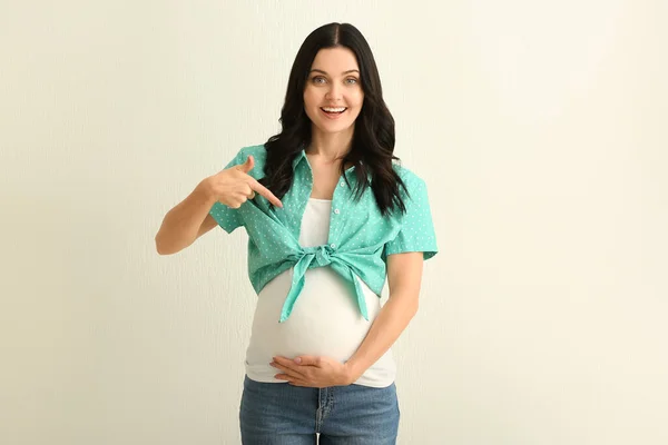 Schöne junge schwangere Frau auf hellem Hintergrund — Stockfoto