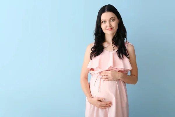 Schöne junge schwangere Frau auf farbigem Hintergrund — Stockfoto
