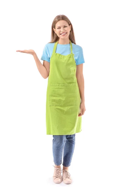 Beautiful young woman in apron showing something on white background — Stock Photo, Image