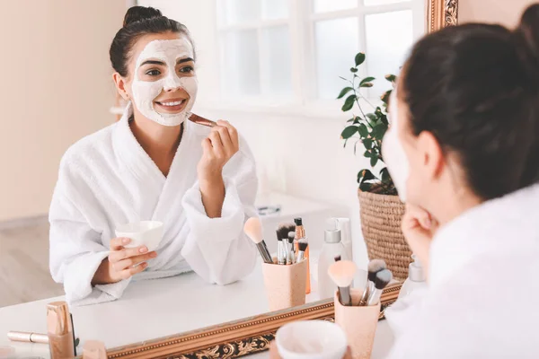 Mooie jonge vrouw die gezichtsmasker thuis toepast — Stockfoto