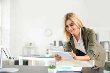 Ofisinde tablet bilgisayarı olan güzel bir iş kadını.