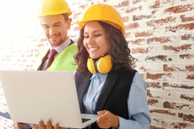 Duvara dizüstü bilgisayarı dayanmış mimarların portresi