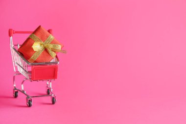 Arkaplanda hediye kutusu olan küçük alışveriş arabası