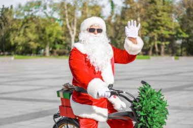 Noel Baba dışarıda bisiklet sürüyor.