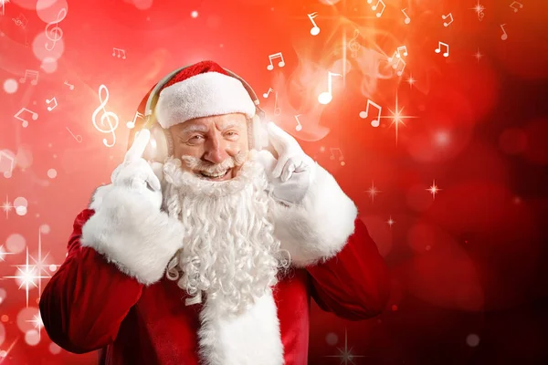 Porträt des Weihnachtsmannes, der Musik auf farbigem Hintergrund hört — Stockfoto