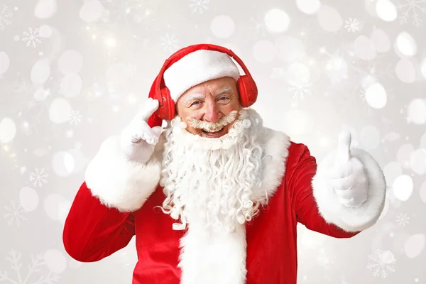 Portrait of Santa Claus listening to music on light background — Stock Photo, Image