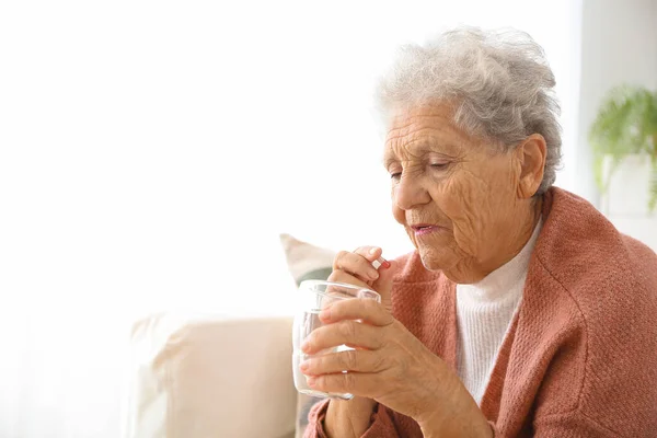 Elderly woman taking medicine at home — Stock Photo, Image
