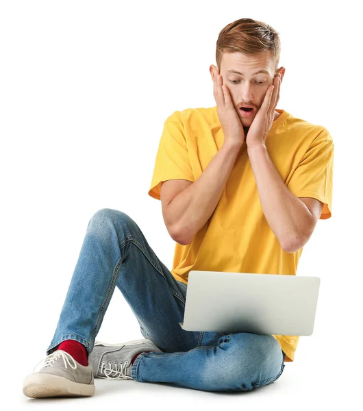 Hombre sorprendido en elegante camiseta y con ordenador portátil sobre fondo blanco — Foto de Stock