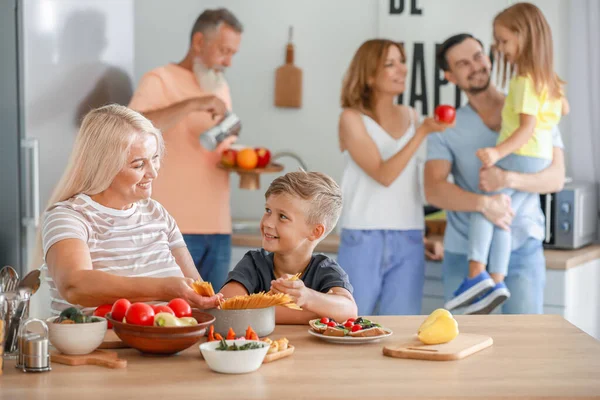 Torunu olan olgun bir kadın mutfakta yemek pişiriyor. — Stok fotoğraf