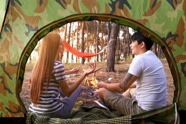 Happy couple roasting marshmallows on fire at camp — Stock Photo, Image