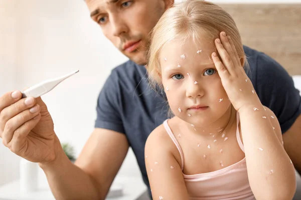 Hombre midiendo la temperatura de su pequeña hija enferma de varicela en casa — Foto de Stock