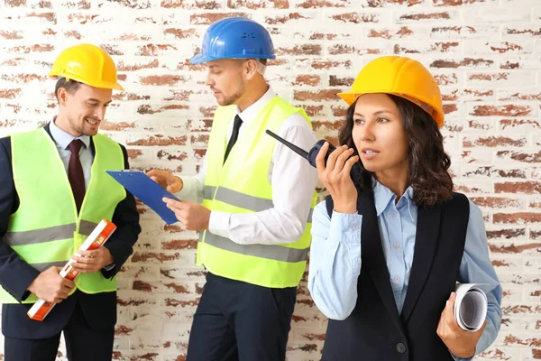 Portrait of female architect and her team against brick wall — Stock Photo, Image