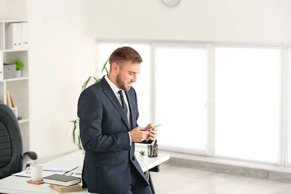 Portrait of handsome businessman with mobile phone in office — Stock Photo, Image