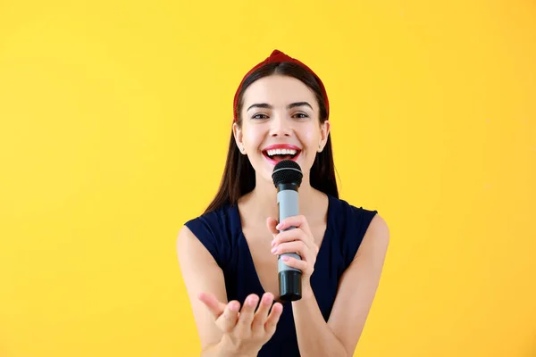 Vacker ung kvinnlig sångare med mikrofon på färg bakgrund — Stockfoto