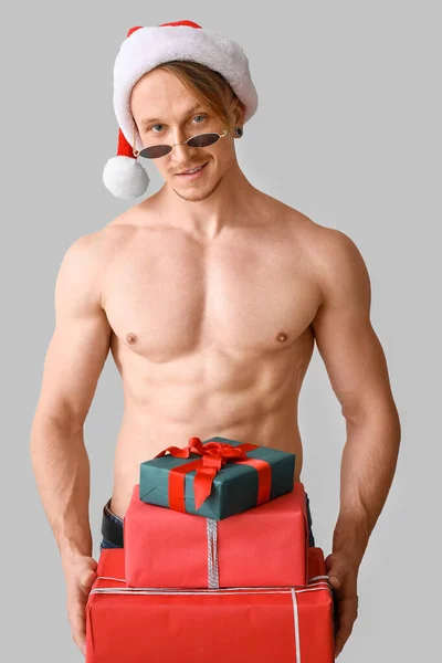 Молодий спортсмен Санта Клаус з дарами на сірому фоні. — стокове фото