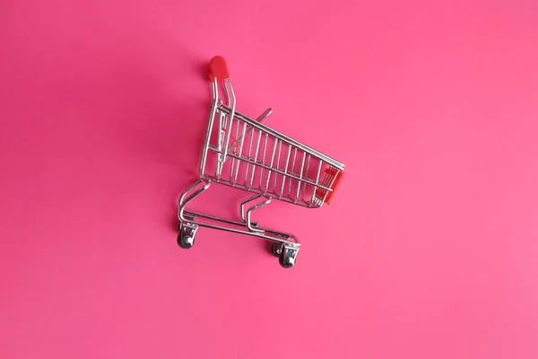 Carrito de compras pequeño vacío sobre fondo de color —  Fotos de Stock