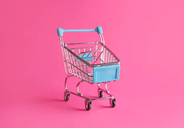 Carrito de compras pequeño vacío sobre fondo de color —  Fotos de Stock