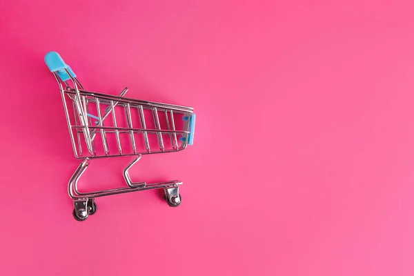 Carrito de compras pequeño vacío sobre fondo de color —  Fotos de Stock