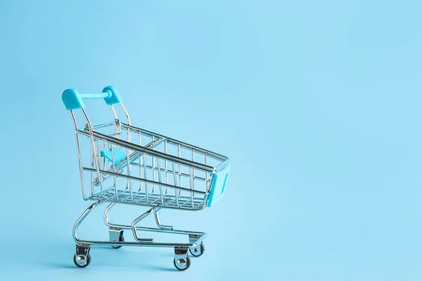 Empty small shopping cart on color background — Stock Photo, Image