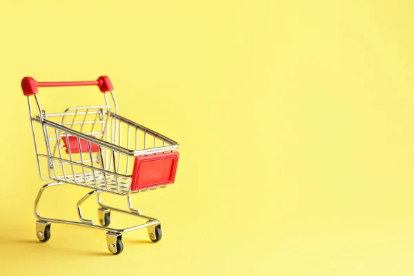 Empty small shopping cart on color background — Stock Photo, Image