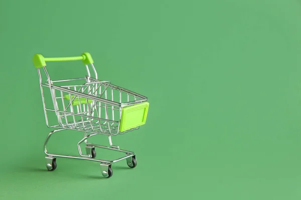 Carrito de compras pequeño vacío sobre fondo de color —  Fotos de Stock