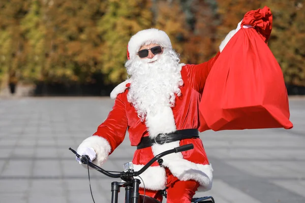 Papai Noel com saco de andar de bicicleta ao ar livre — Fotografia de Stock